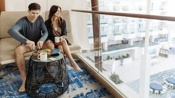 A couple sitting on a sofa by a large window overlooking a residential area.