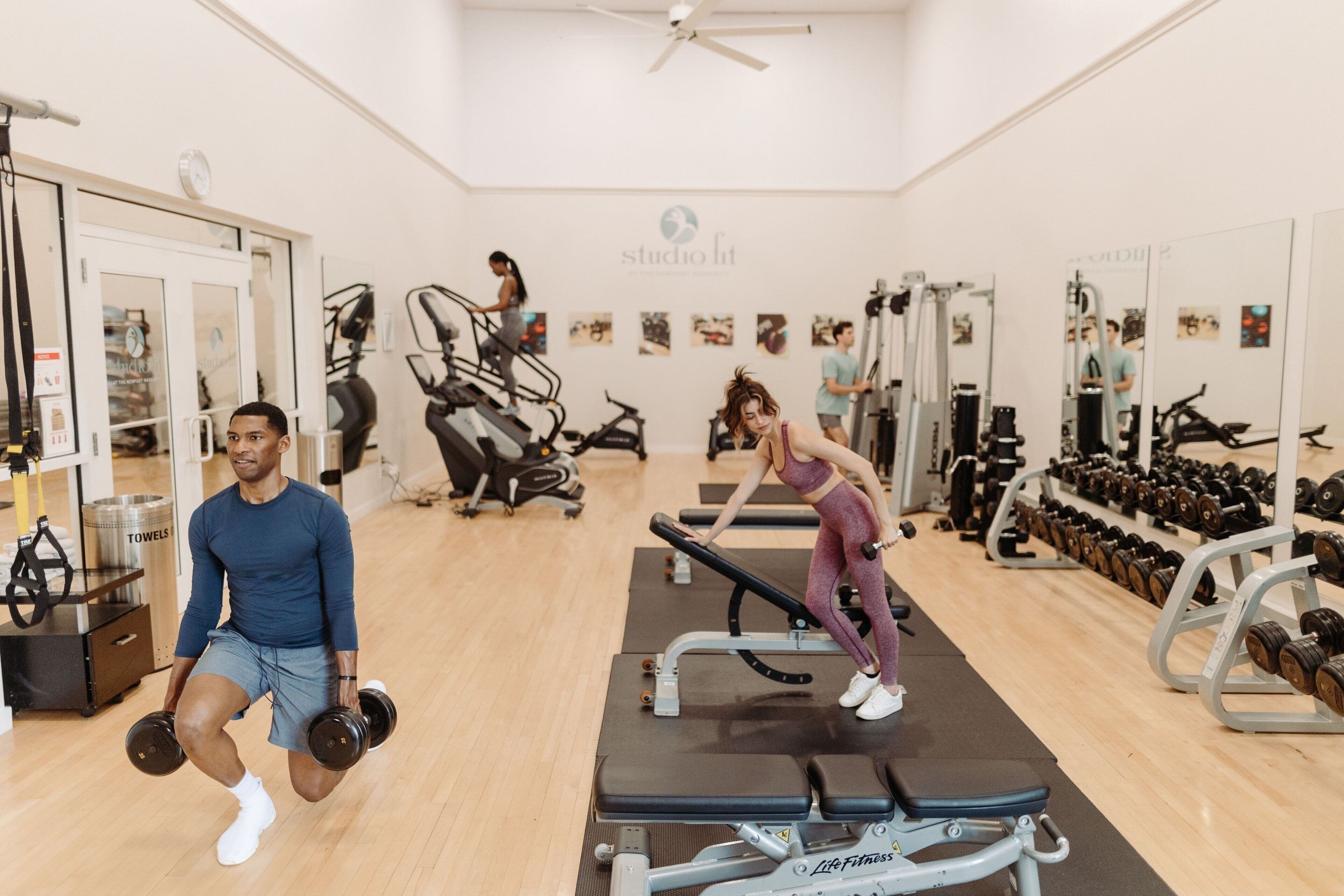 A gym with exercise equipment, a mirror, and a clock on the wall.