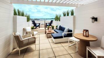 A patio with a sofa, chairs, and a table, overlooking a body of water.