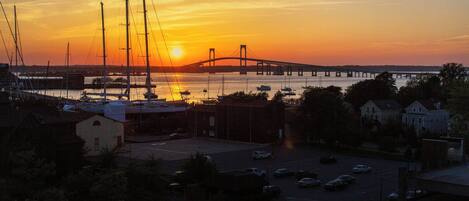A sunset view over a bridge, boats, and a parking lot with buildings in the foreground.