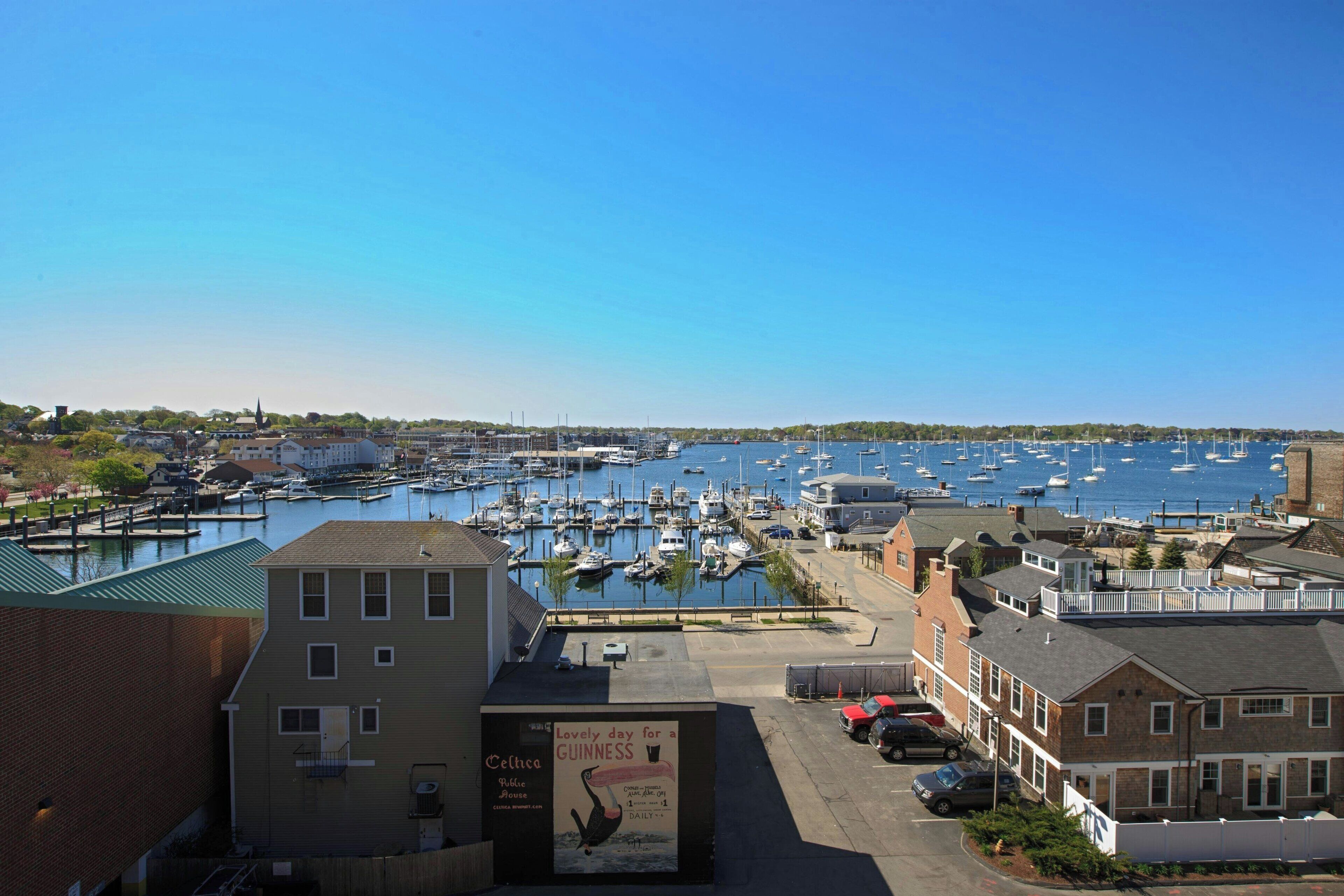 A marina with boats docked, buildings, and a clear sky.