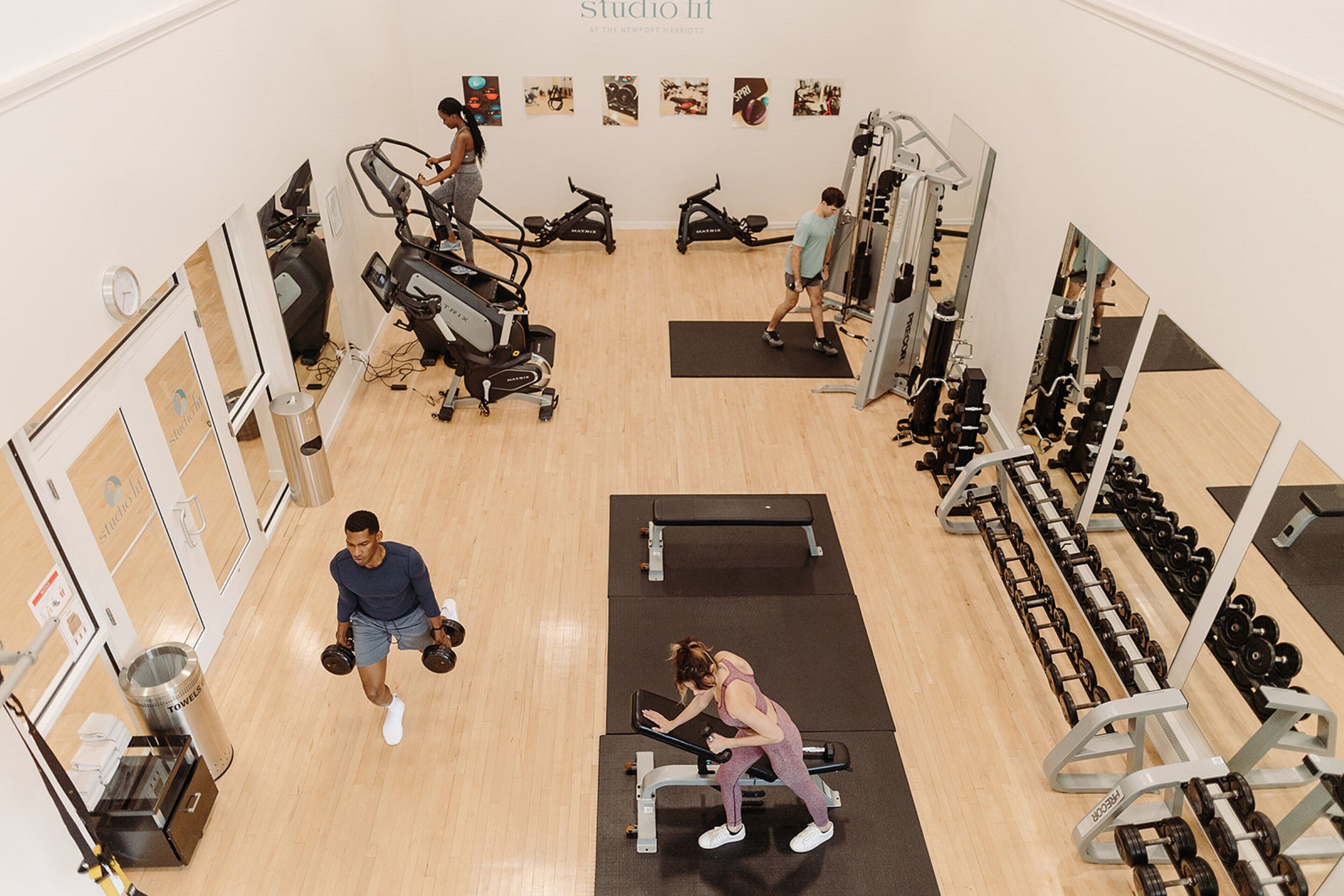 Uma academia com equipamentos de cardio, estações de musculação e espelhos.