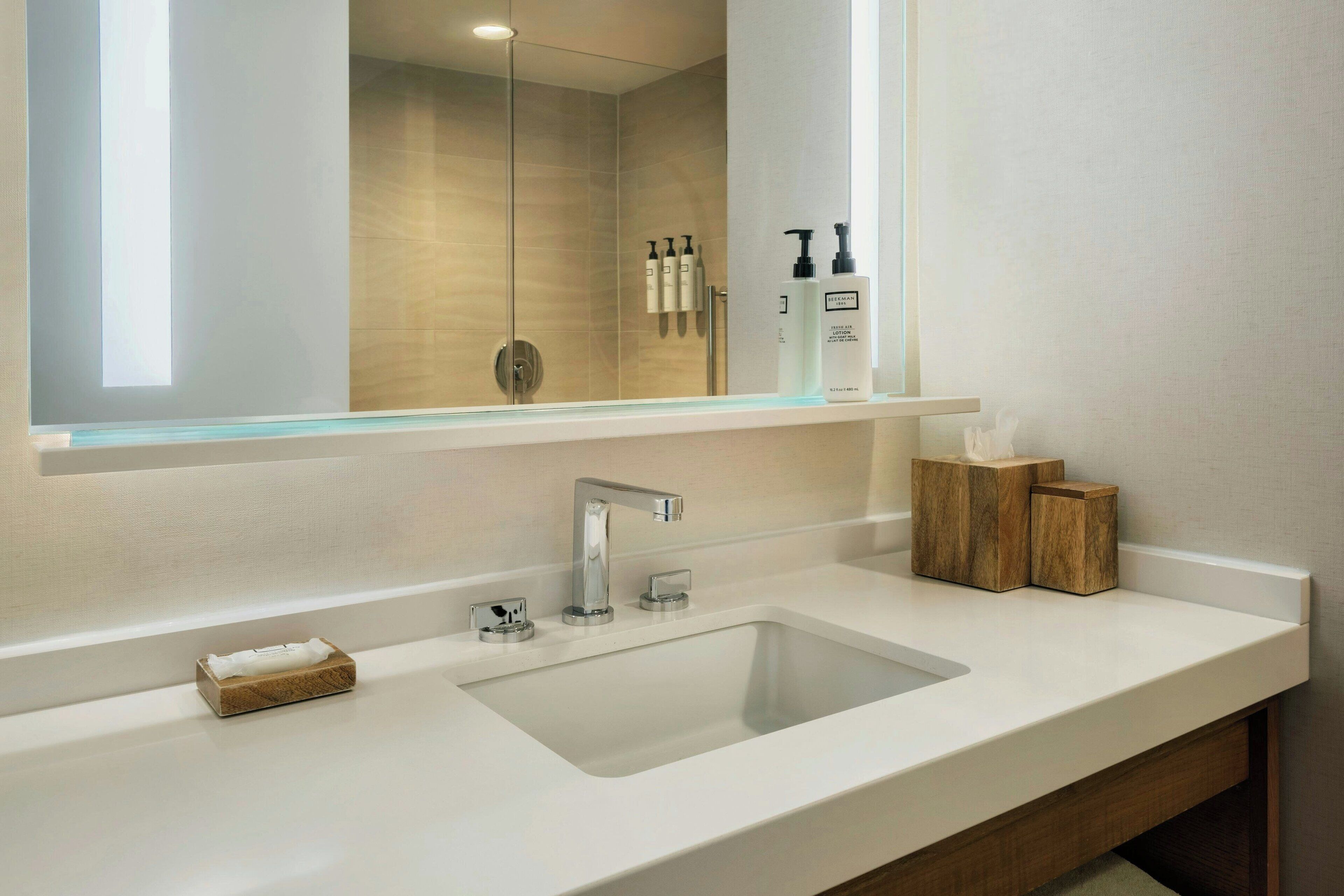 A modern bathroom with a large mirror, a chrome sink, and a glass-enclosed shower.