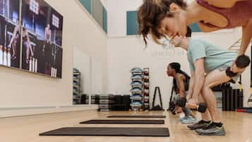 A gym with exercise mats, dumbbells, and a wall with posters.