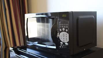 A microwave with a digital display and control panel, placed on a black surface.