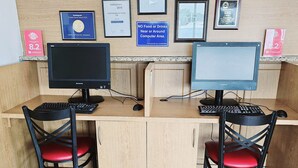 A reception desk with two computer stations, each with a monitor, keyboard, and chair. There are framed awards and certificates on the wall, and a sign indicating no food or drinks near the computer area. - Quality Inn Florida City - Gateway to the Keys (Florida City)