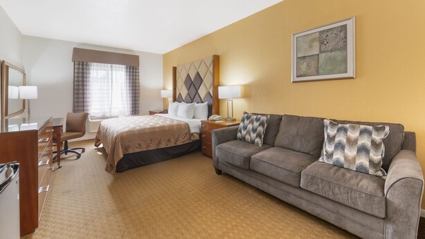 A hotel room with a bed, a sofa, a desk, and a chair. - Quality Inn Florida City - Gateway to the Keys (Florida City)
