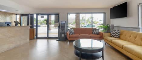 A reception area with a reception desk, an ATM, a sofa, and a coffee table.