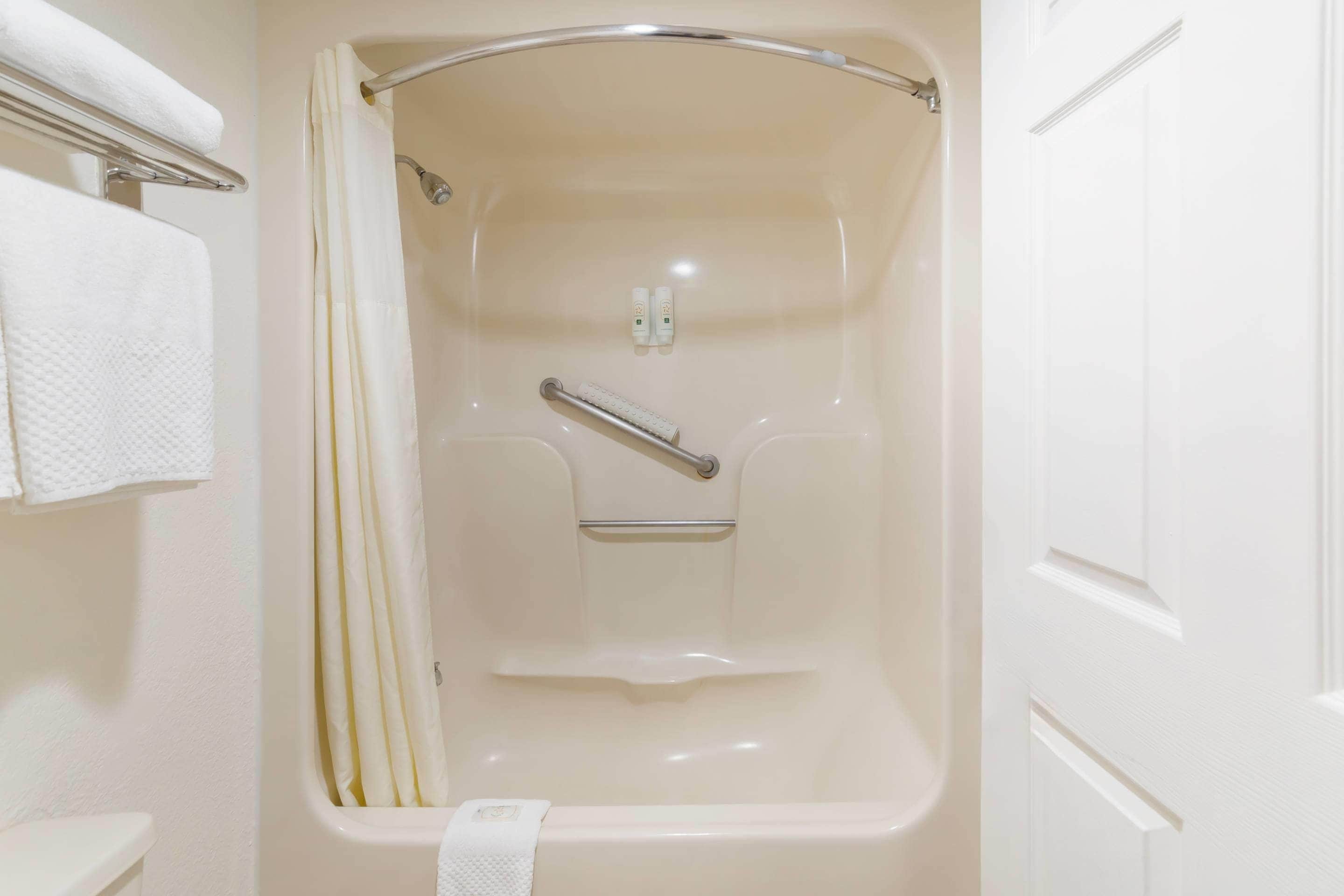 A white bathtub with a shower curtain, a grab bar, and a towel rack.