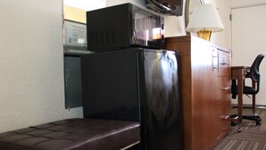 A compact room with a wooden desk, a chair, a bench, and a refrigerator. - Quality Inn Florida City - Gateway to the Keys (Florida City)