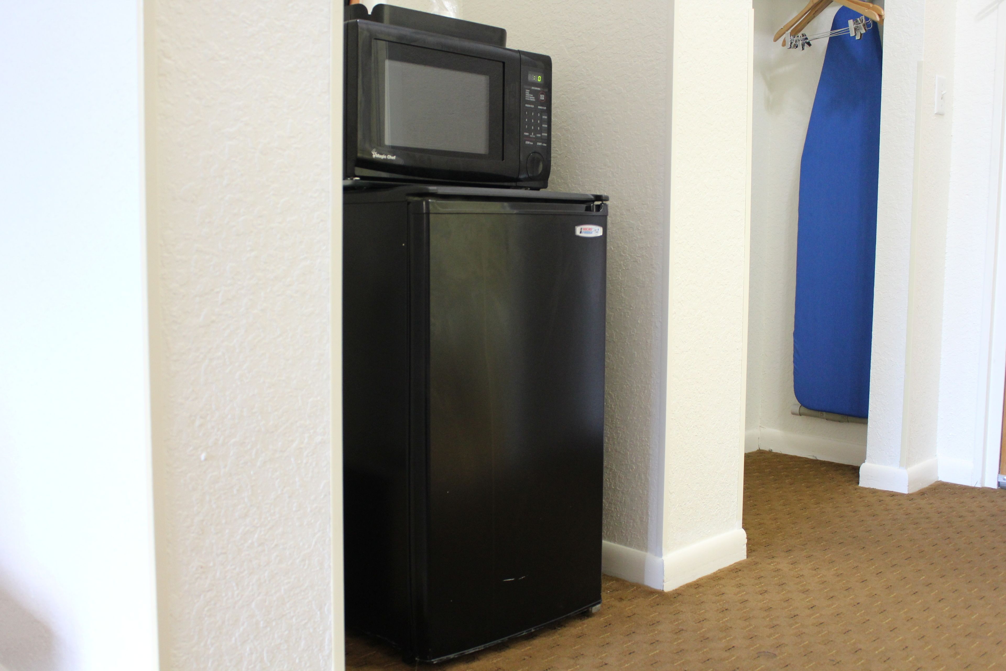 Eine kleine Küchenzeile mit einem schwarzen Kühlschrank und einer Mikrowelle.