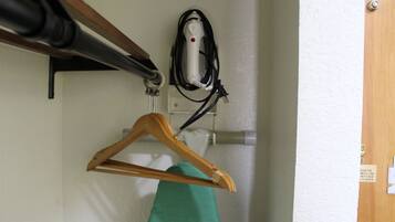 A wooden hanger with a green garment hanging on it, a hairdryer, and a wall-mounted electrical outlet.