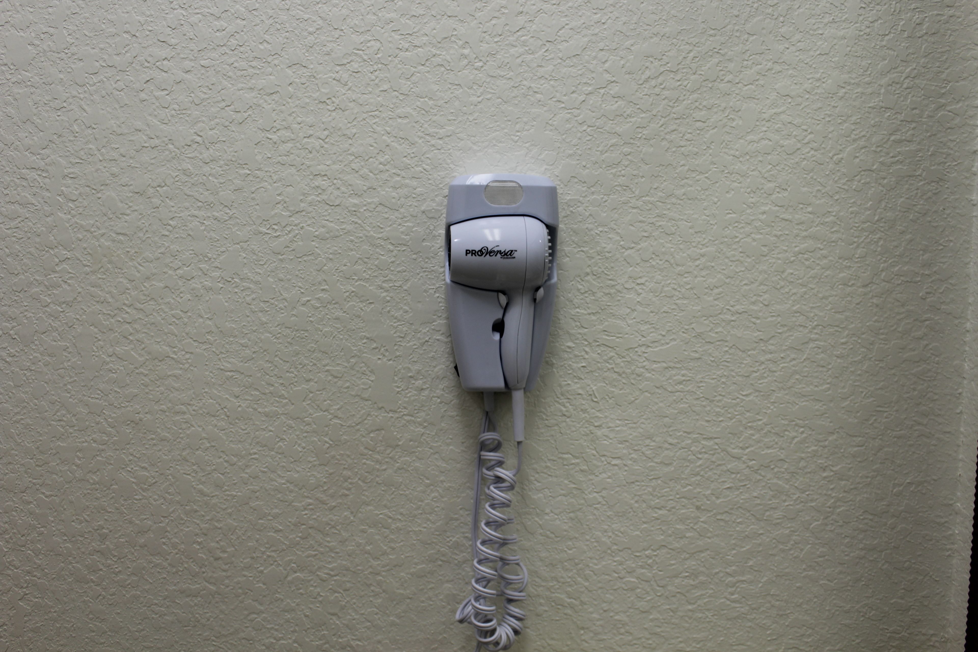 Un sèche-cheveux fixé sur un mur à texture.