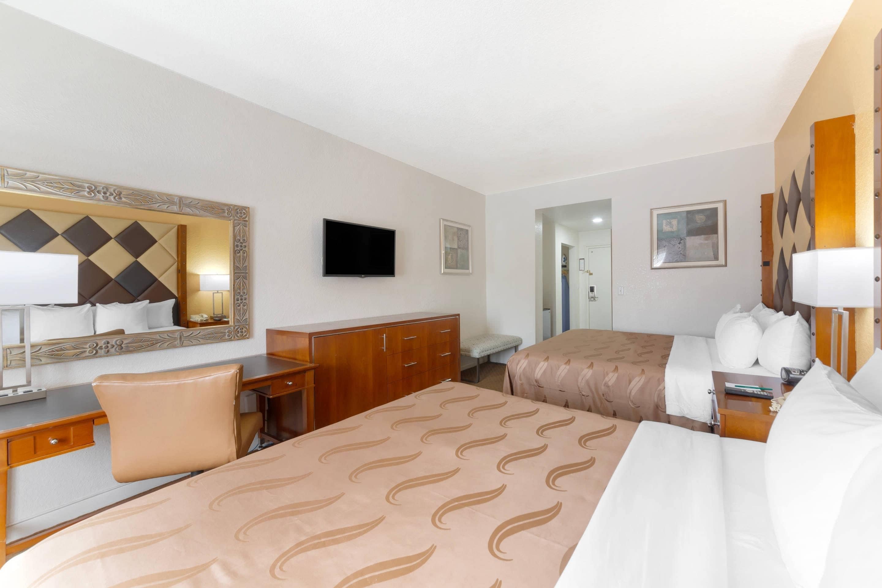 Ein Hotelzimmer mit einem Bett, einem Schreibtisch, einem Stuhl, einem Schminktisch und Bildern an den Wänden.