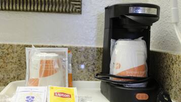 Una cafetera con espumador de leche y una bandeja con cápsulas de café y una bolsita de té Lipton.