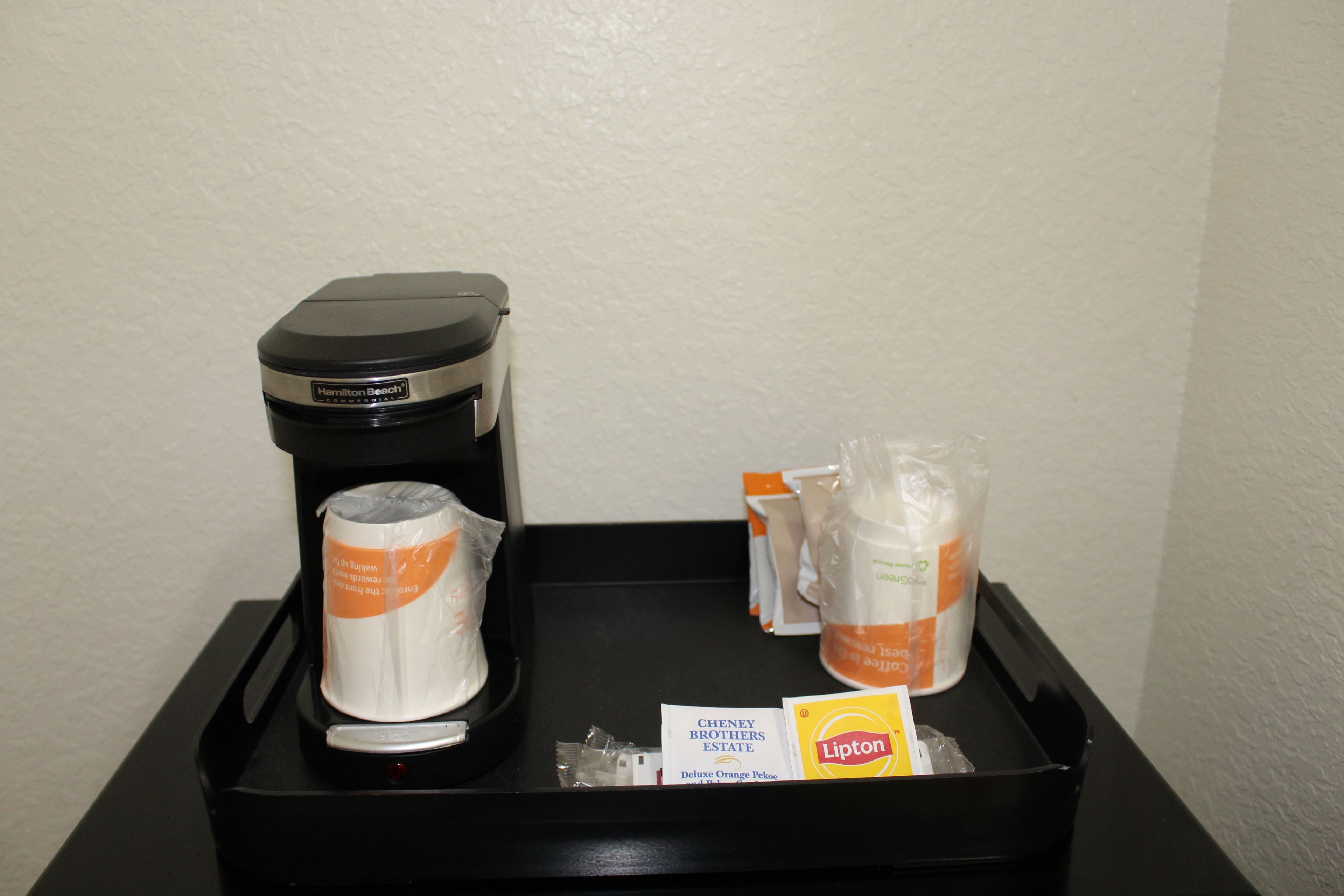 Dans une chambre d’hôtel, on trouve un mini-bar, une machine à café, des gobelets jetables, une boîte de thé Lipton et un sachet de thé noir décaféiné de la marque Cheney Brothers Estate.