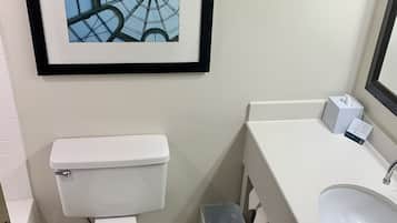 A bathroom with a toilet, sink, and framed artwork on the wall.