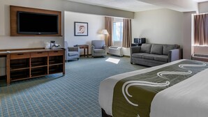A hotel room with a bed, a desk, a television, a chair, a sofa, and a window with curtains. - Quality Inn Lexington -Horse Park (Lexington)