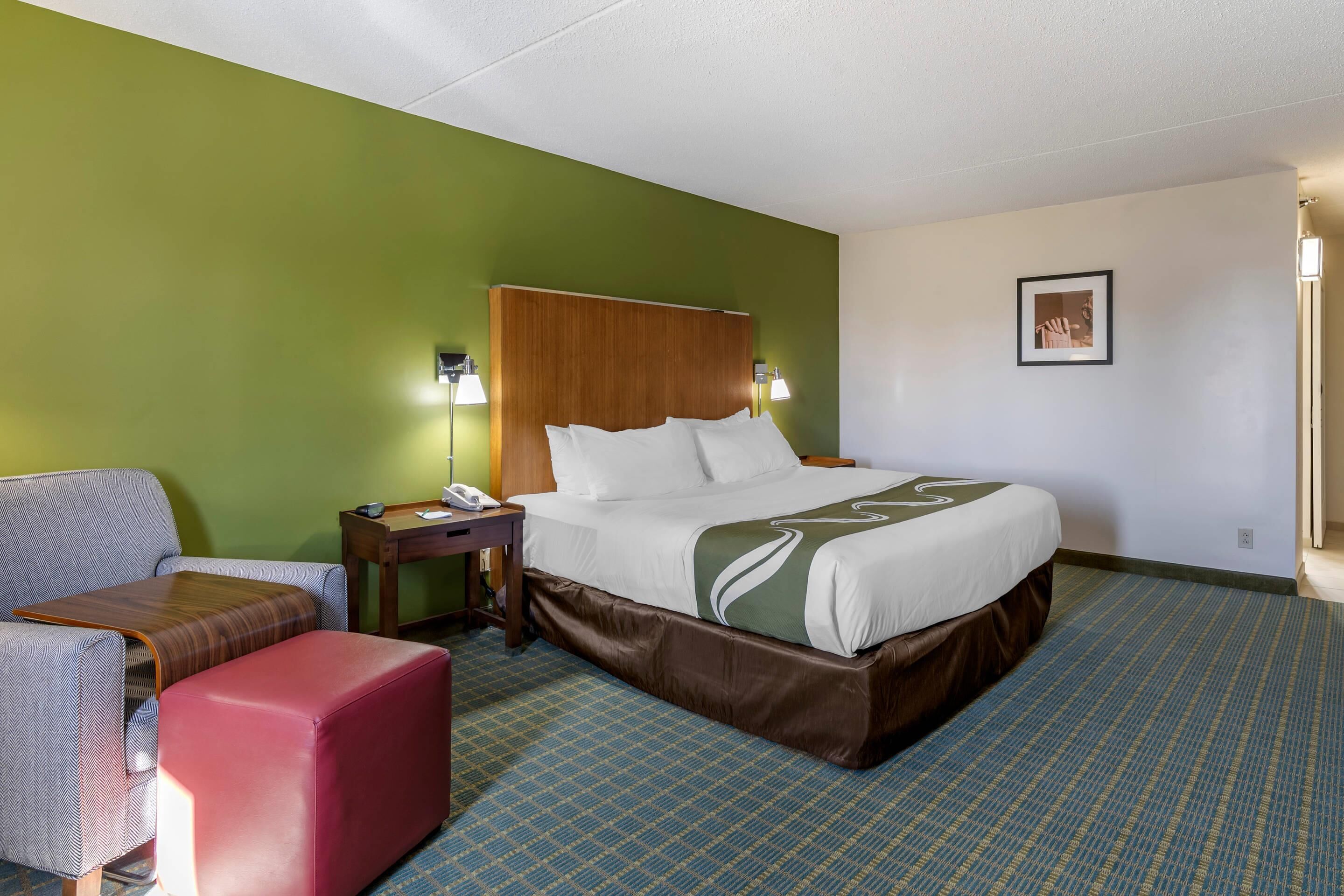 Ett hotellrum med en säng, ett skrivbord, en stol och en soffa.