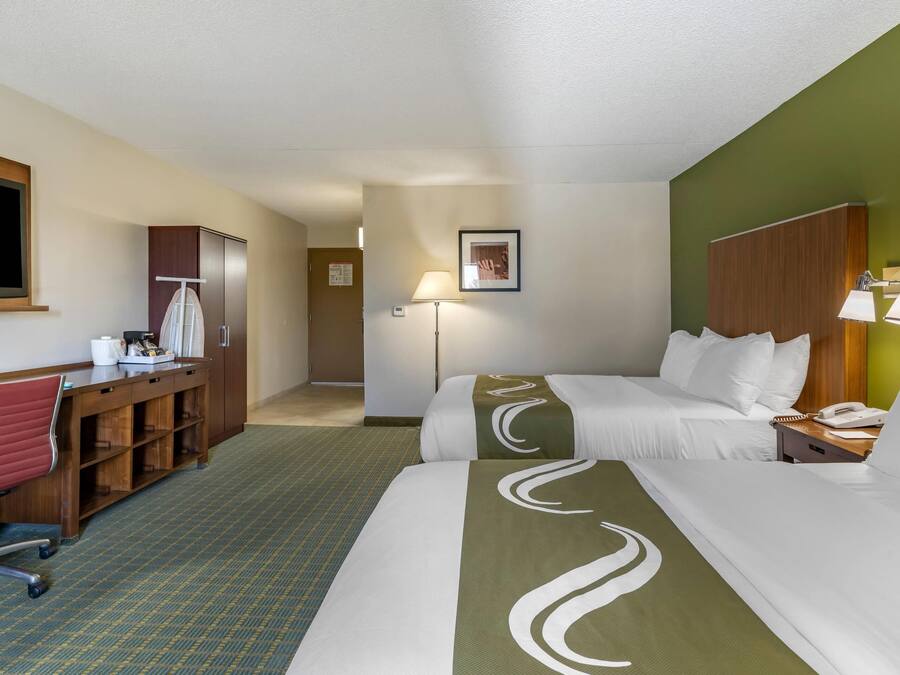 Une chambre d’hôtel avec un lit, un bureau, une chaise et une lampe.