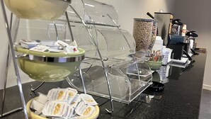 A buffet setup with clear glass serving stations and a coffee machine in the background. - Quality Inn Lexington -Horse Park (Lexington)