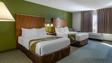 Quarto de hotel com duas camas, uma parede verde, um carpete estampado e uma janela com cortinas.