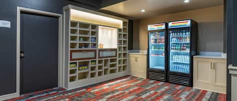 Un pasillo con alfombra estampada, una kitchenette con refrigerador, y un cartel que indica el MainStay Marketplace.