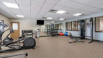 Un gimnasio con cintas de correr, máquinas de pesas y pelotas de ejercicio.
