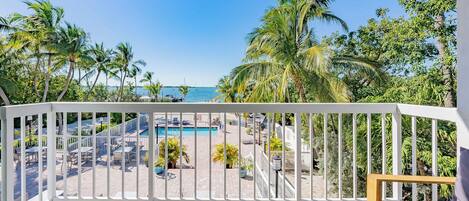 A balcony with a view of a pool and palm trees.