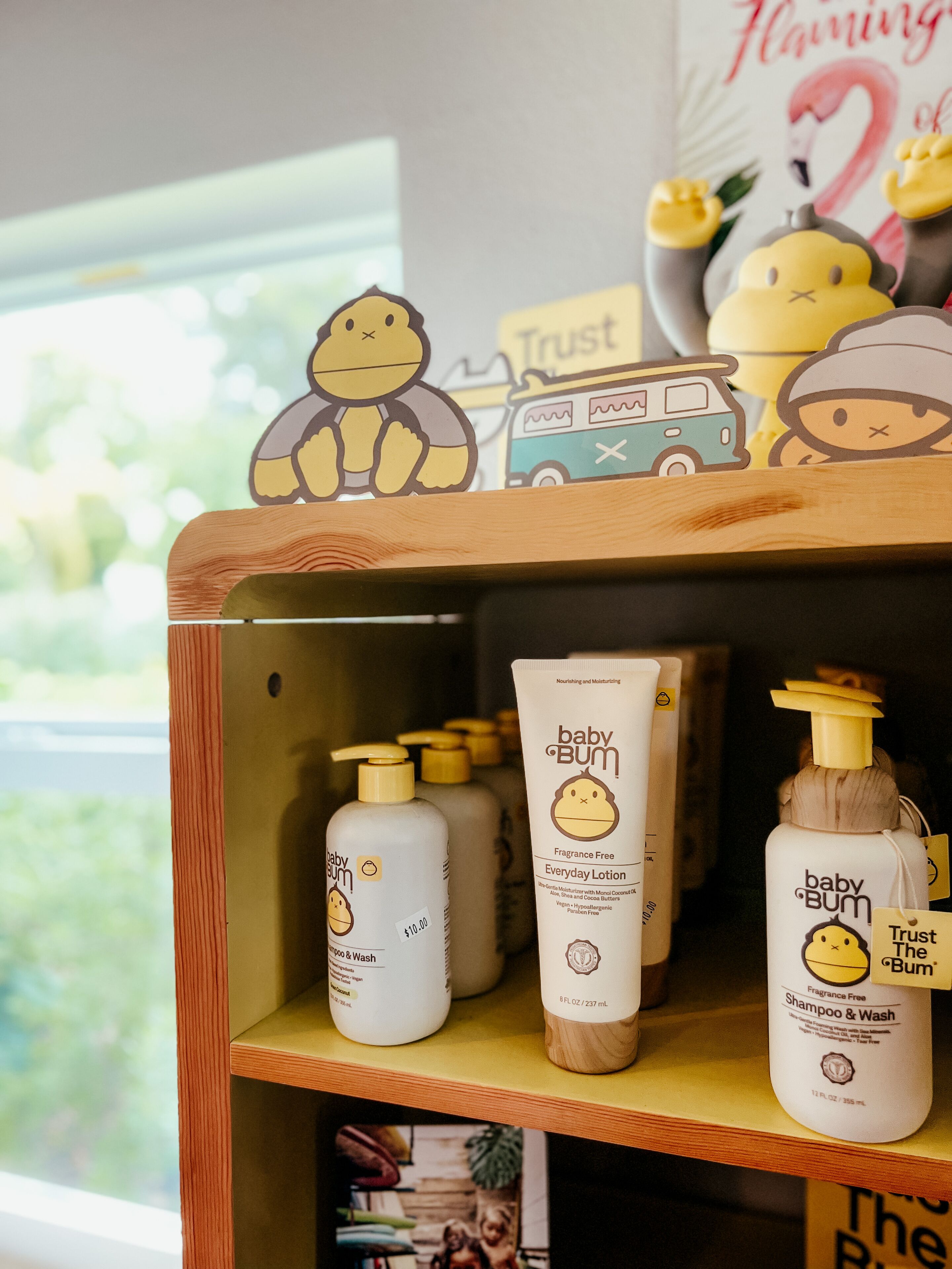 Une étagère contenant des produits de soins pour bébés, notamment des shampoings et des lotions, avec un fond en bois et une fenêtre en arrière-plan.