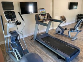 A home gym with treadmills, a stair climber, and a weight bench.