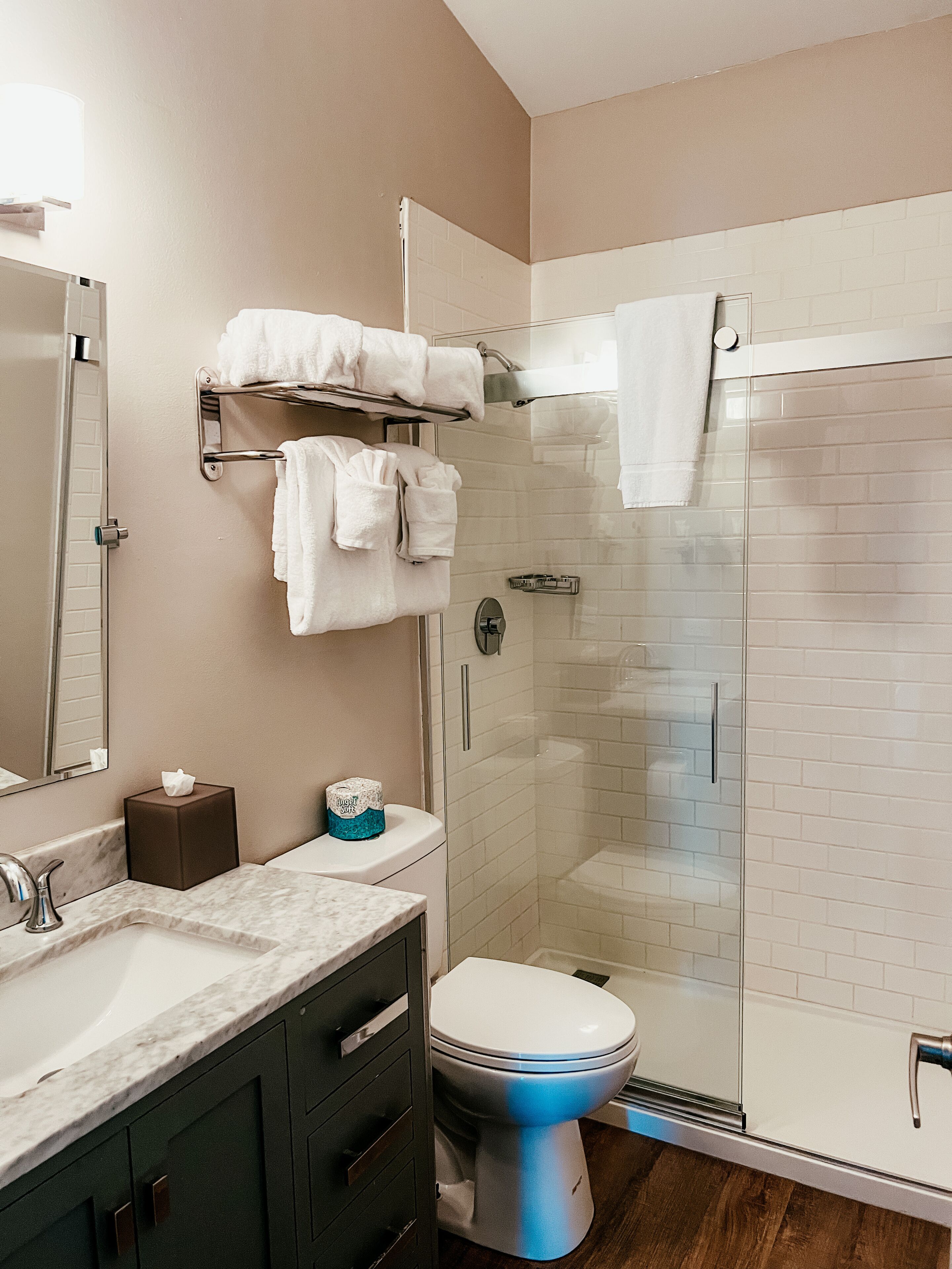 Une salle de bain moderne avec une douche à parois de verre, des toilettes blanches et un lavabo en marbre.