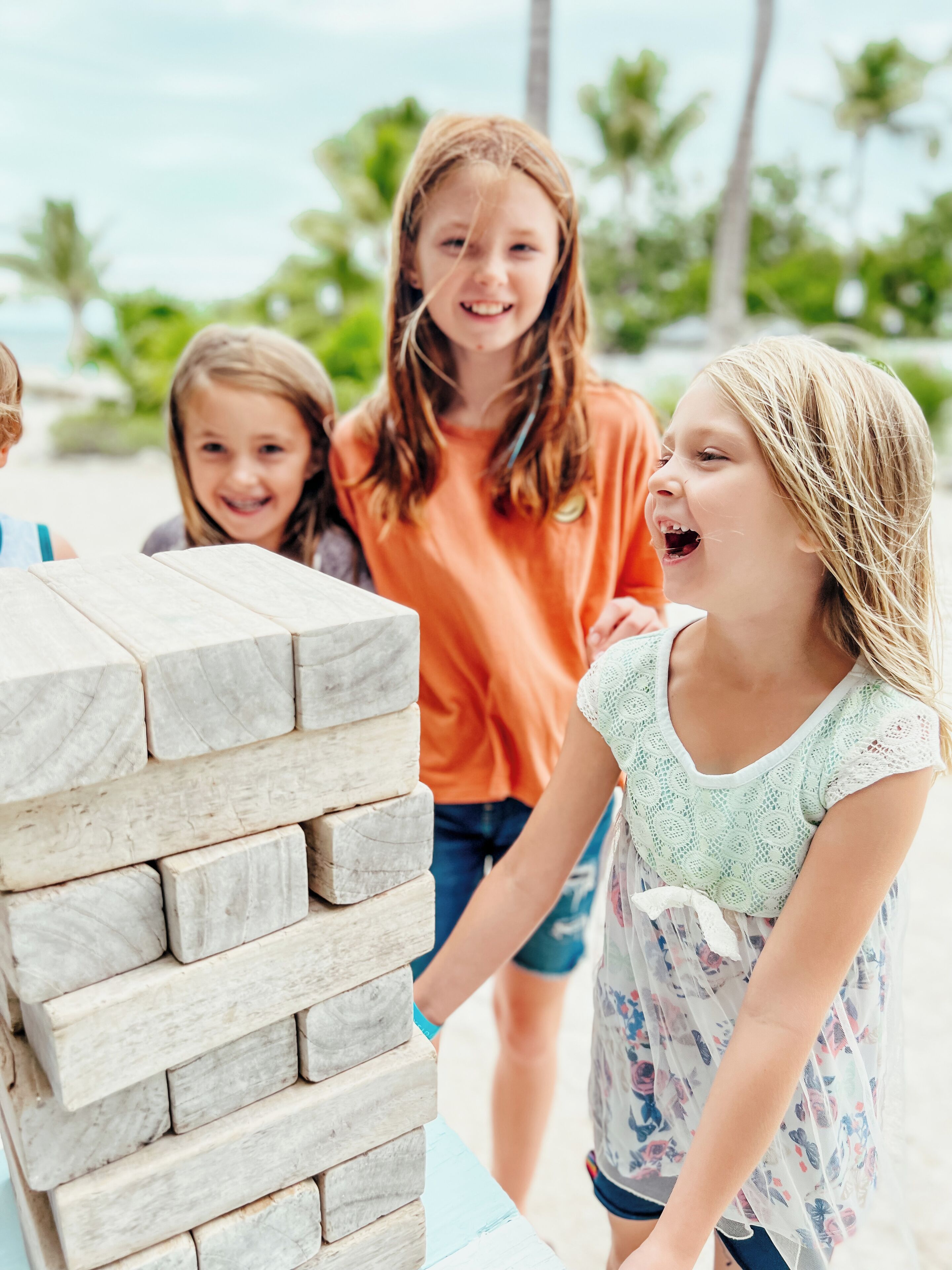 Een groep kinderen speelt een spel met een stapel houten blokken.