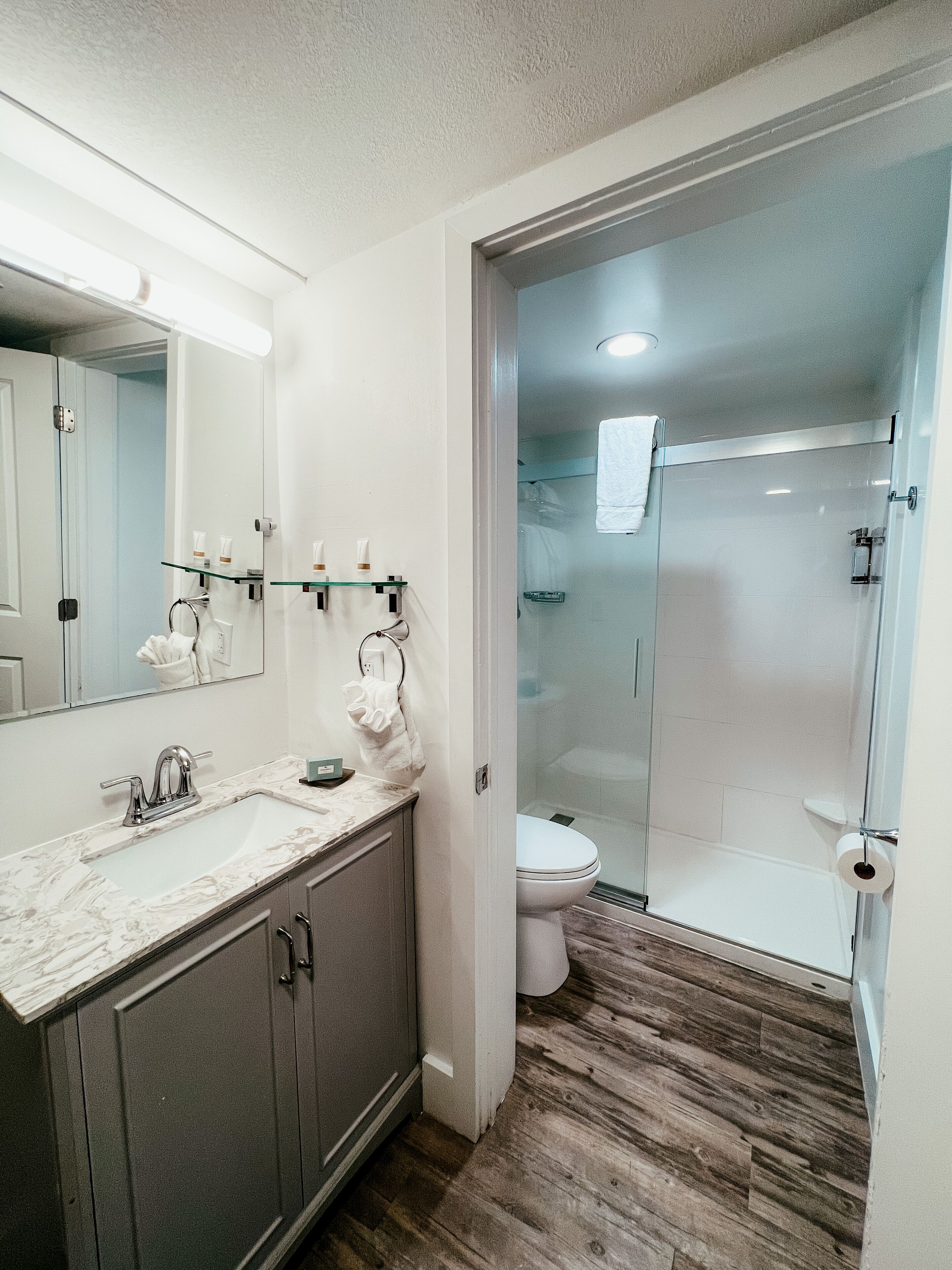 A modern bathroom with a marble sink, a glass shower enclosure, and a toilet.