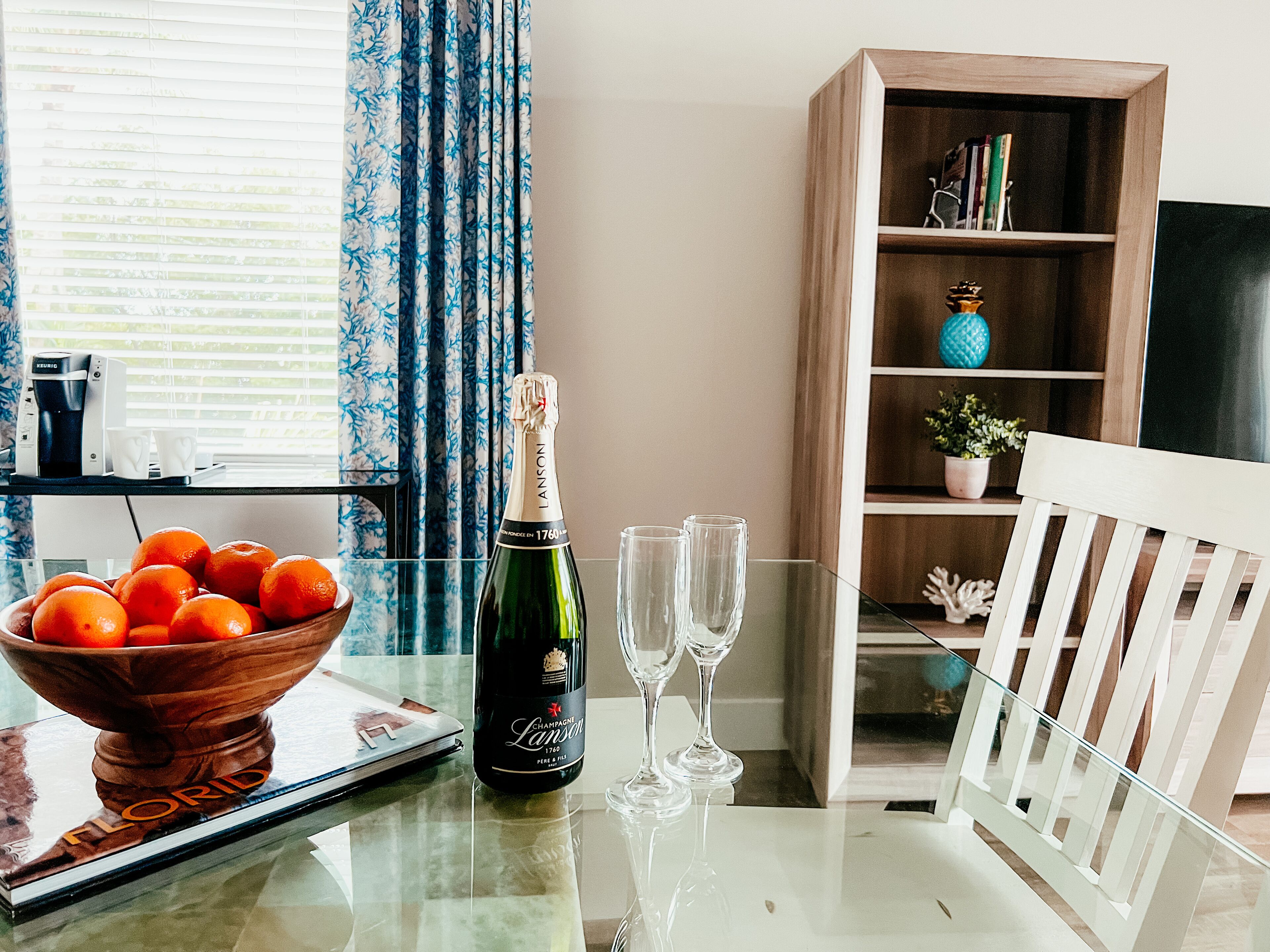 Een tafel met een champagnefles, twee glazen, een schaal mandarijnen en een tijdschrift.