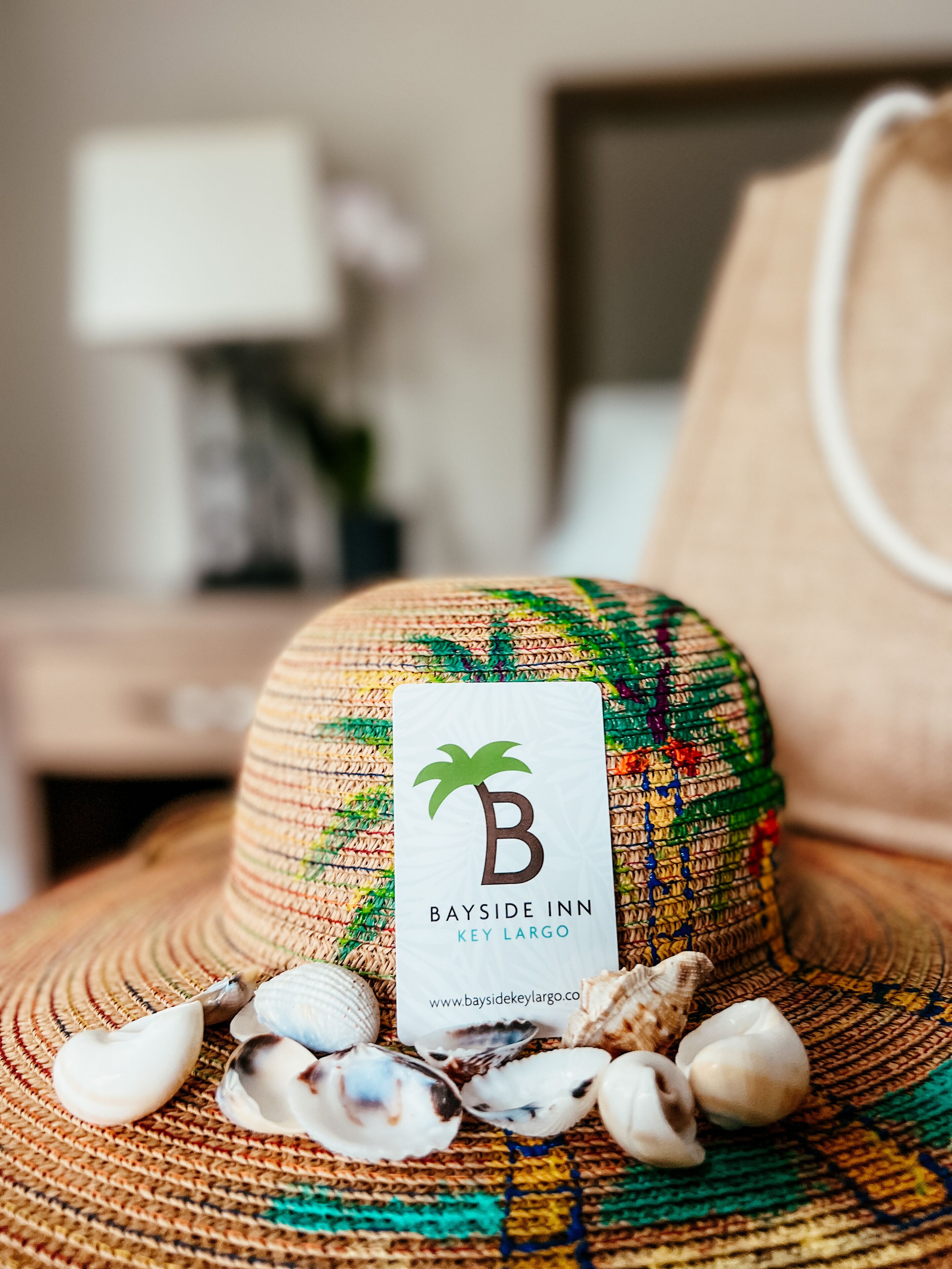 A straw hat with a label for Bayside Inn Key Largo, surrounded by seashells.
