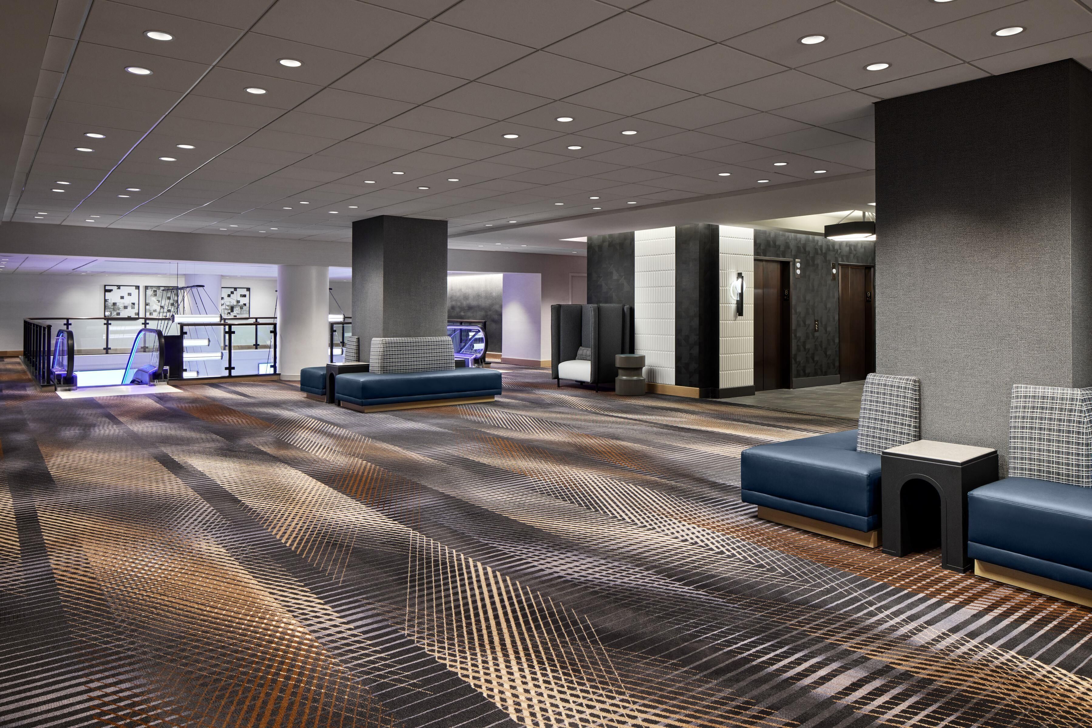 Un hall d’entrée spacieux, doté d’un tapis à motifs, de coins salon et d’un comptoir d’accueil.