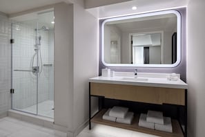 A modern bathroom with a glass-enclosed shower, a wooden vanity with a mirror, and neatly folded towels. - Hyatt Regency Washington on Capitol Hill (Washington)