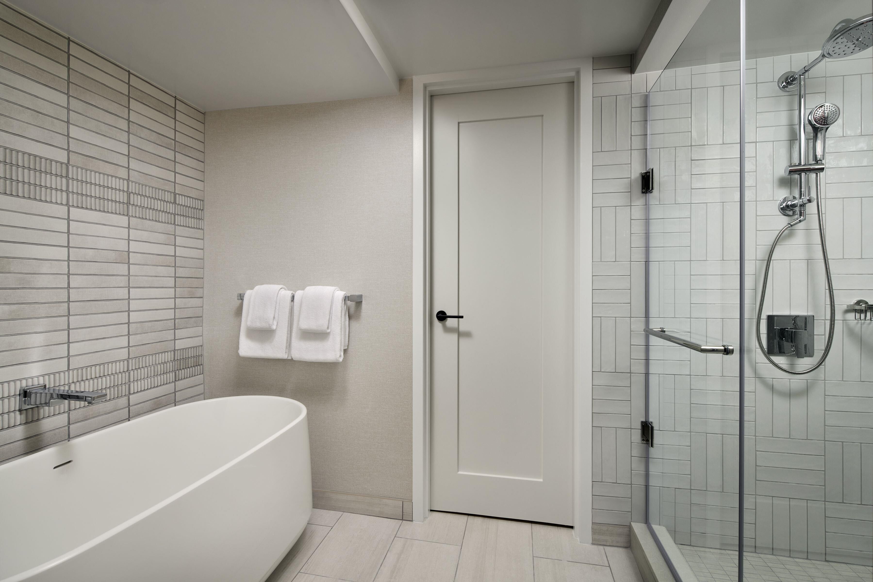 Une salle de bain moderne avec une baignoire, une douche et une porte.
