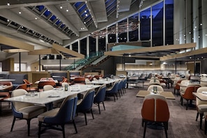 A spacious dining area with multiple tables and chairs, a staircase, and large windows allowing natural light. - Hyatt Regency Washington on Capitol Hill (Washington)