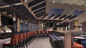 A modern bar area with high stools, a counter with bottles, and a seating area with a sofa and tables. - Hyatt Regency Washington on Capitol Hill (Washington)