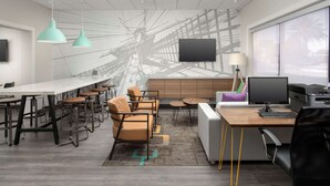 Un espace de bureau moderne avec une longue table blanche, plusieurs chaises, un canapé, un bureau avec un ordinateur et une grande fenêtre.