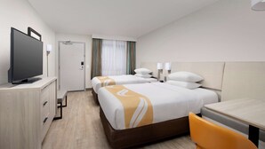 Une chambre d’hôtel avec deux lits, un bureau, une télévision et une chaise.