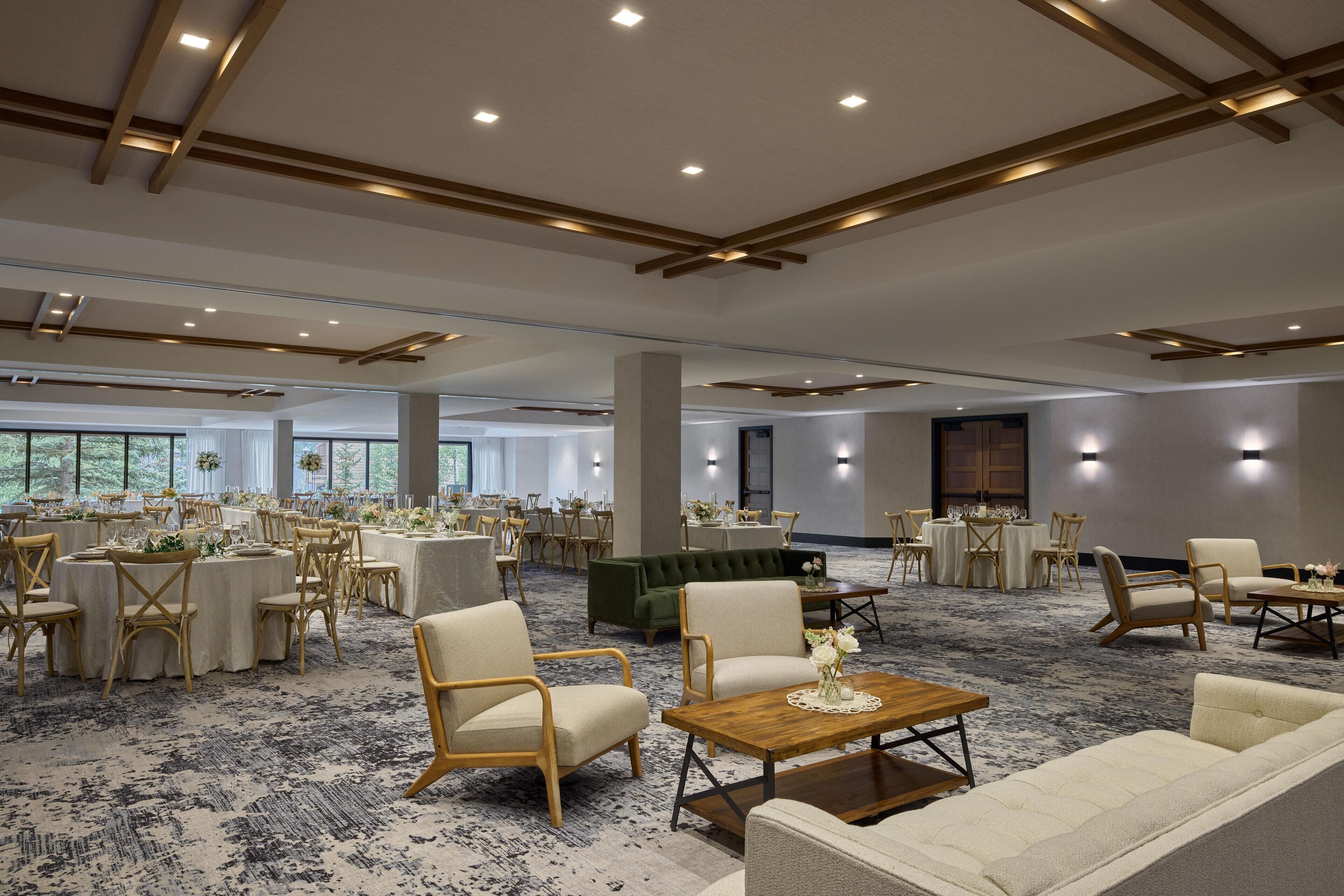 A spacious hotel lobby with round tables, chairs, and a green sofa.