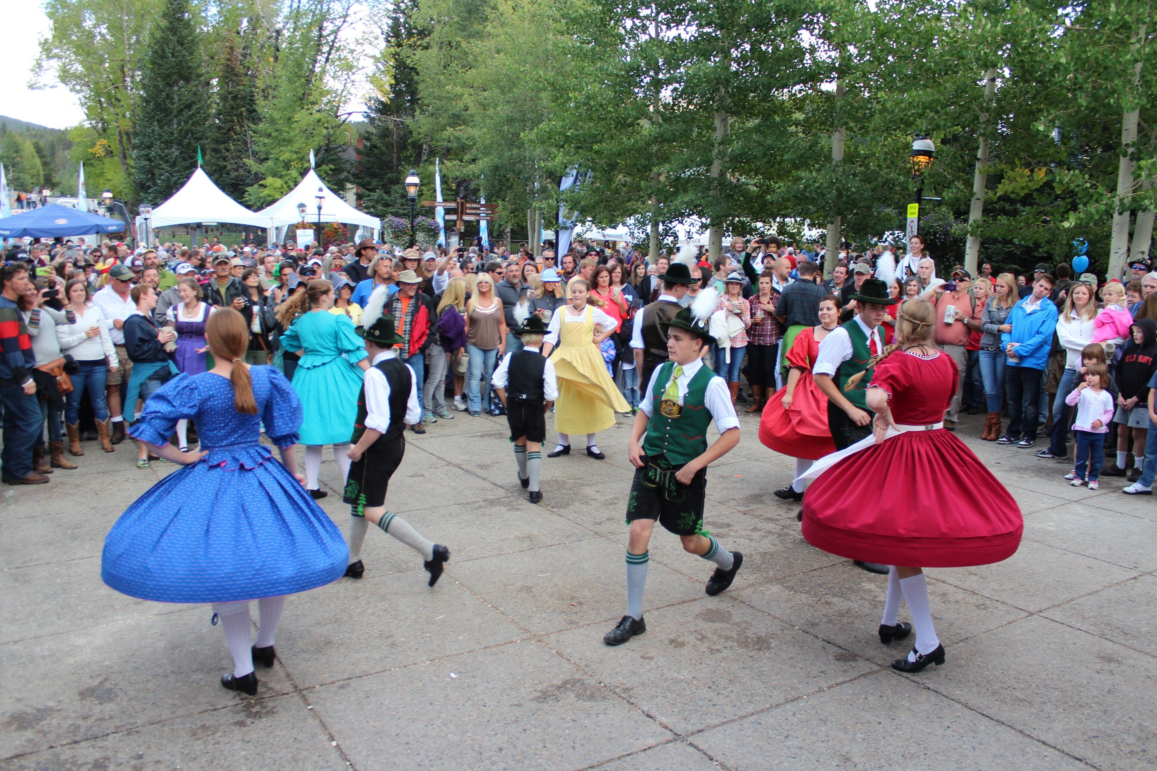 Eine Gruppe von Menschen in traditioneller Tracht durchschreitet einen öffentlichen Platz.