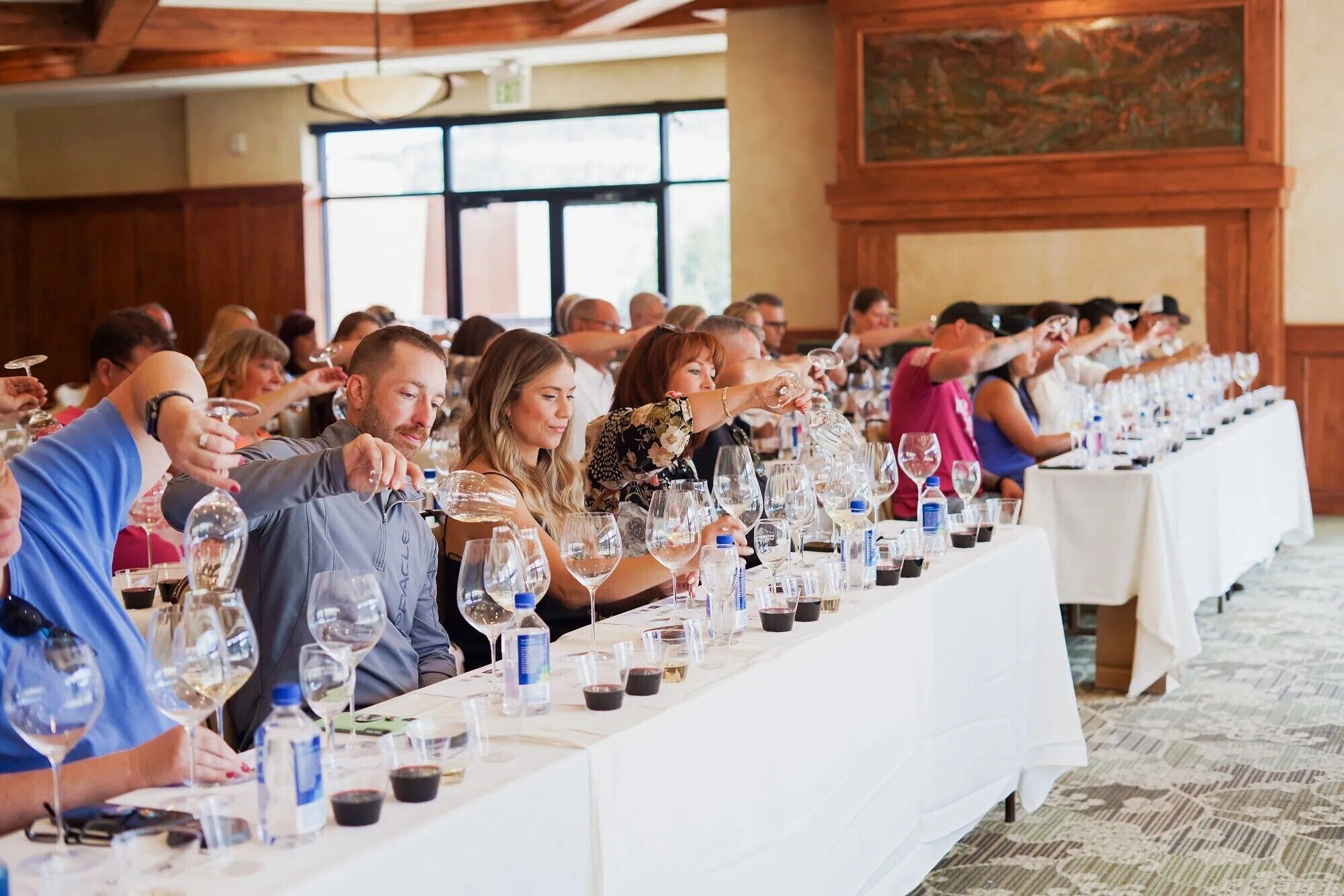 A long dining table with multiple people seated, each with a wine glass.