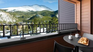 A balcony with a view of a snow-capped mountain, a table with a tray of food, and a chair. - Hotel Alpenrock Breckenridge, Curio Collection by Hilton (Breckenridge)