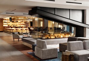 A modern lobby with a bar area, seating, and a fireplace. - Hotel Alpenrock Breckenridge, Curio Collection by Hilton (Breckenridge)