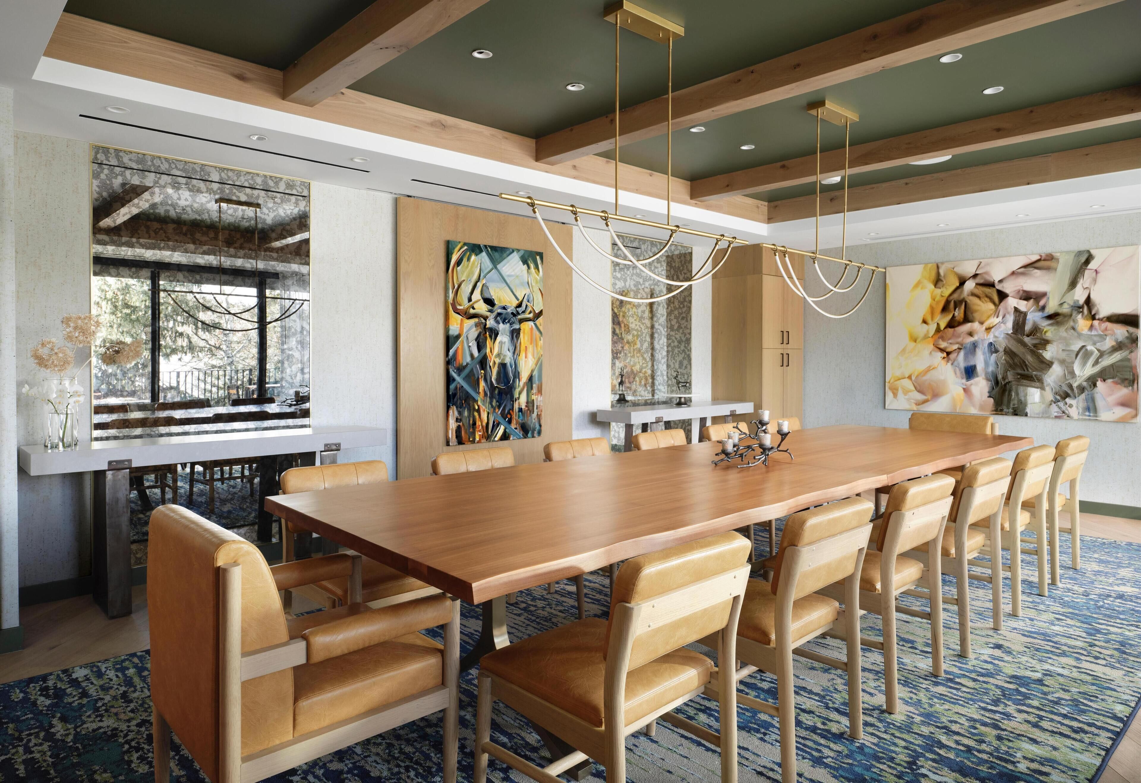 A spacious dining area with a long wooden table and multiple chairs, a chandelier, and artwork on the walls.