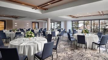 A large banquet hall with round tables, blue chairs, and white tablecloths.